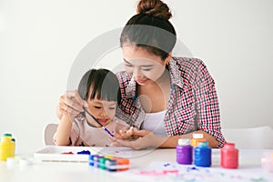 A happy family is painting. Mom help her daughter drawing