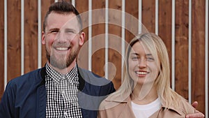 Happy family pair is laughing and looking at camera outdoors, medium shot