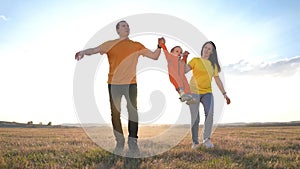 happy family. parent a baby together run in the park at sunset. people in park concept. mom dad daughter fun and son