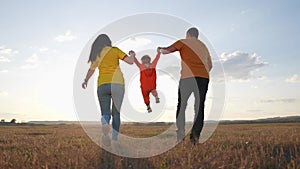 happy family. parent a baby together run in the park at sunset. people in park concept. mom dad daughter and son swing