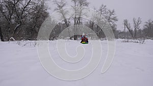 Happy family, parents and child are playing in the Christmas park. Mom and daughter are sledding dad, in the winter