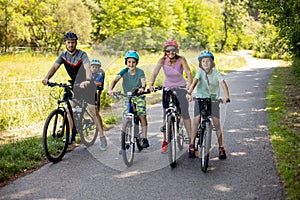Happy family, parents and children, riding bikes in the park on a sunny summer day, enjoying quality family time