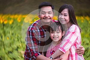 Happy family with parents and daughter, smiling together in sunflower field.Concept of lovely family and travel