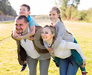 Happy family of parents with two children enjoy a walk in city park