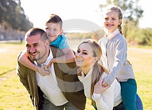 Happy family of parents with two children enjoy a walk in city park