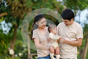 happy family in park. father and mother talking and playing with infant baby