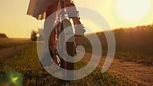 Happy family in the park. Little girl rides a bicycle. The child`s feet are pedaling. The kid is riding at sunset