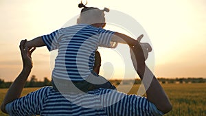 Happy family in park at sunset. Child sits on shoulders of father. Happy family concept. Dad plays with his daughter as