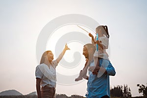 Happy family in the park sunset light. family on weekend running together in the meadow with river Parents hold the child hands.