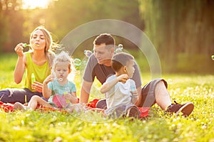 Happy family in the park together on a sunny day - children blow