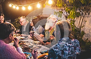 Happy family people having fun at barbecue dinner - Multiracial friends eating at bbq meal - Food, friendship, gathering and