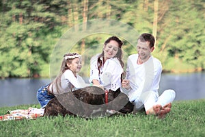 Happy family with pet dog at picnic in a Sunny summer day. pregn