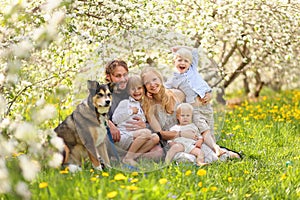 Happy Family and Pet Dog Relaxing in Flower Orchard