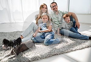 Happy family with pet sitting on the carpet