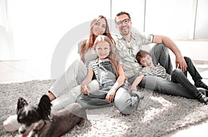 Happy family with pet sitting on the carpet