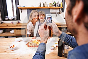 Happy family, phone and picture in kitchen for baking pizza together with parents in home. Photography, cooking and