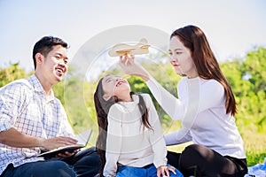 Happy family picnic. Asian parents Father, Mother and daughter playing the toy airplane and have enjoyed ourselves together whil