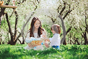 Happy family on picnic for mothers day. Mom and toddler son eating sweets outdoor in spring