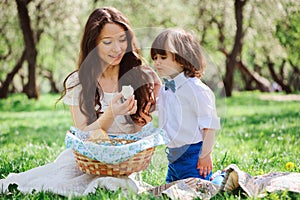 Happy family on picnic for mothers day. Mom and toddler son eating sweets outdoor in spring or summer