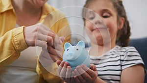 happy family piggy bank. mom and daughter a put coins future in the piggy bank. mortgage loan savings home in crisis