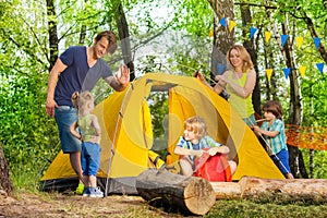 Happy family pitching up a tent in the forest