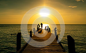 Happy family play together on summer vacation at wooden bridge at sunset. Parent and children playing at the beach on holiday.