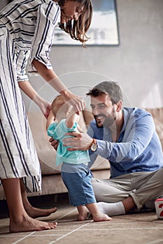 Happy family playing and baby learning to walk at home