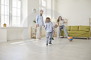 Happy family playing ball and having fun together in living room of their new house