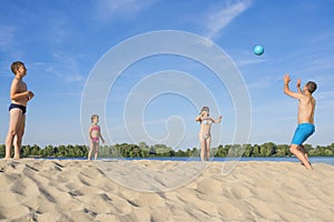 Happy family playing beach volleyball by the river on a sunny day. lifestyle. Summer holidays