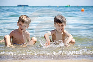 Happy family playing in blue water of swimming pool on a tropical resort at the sea. Summer vacations concept. Two brother kids