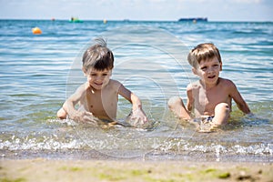 Happy family playing in blue water of swimming pool on a tropical resort at the sea. Summer vacations concept. Two brother kids