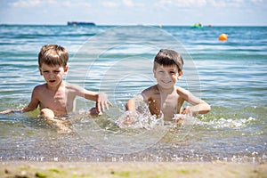 Happy family playing in blue water of swimming pool on a tropical resort at the sea. Summer vacations concept. Two brother kids