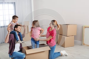 Happy family playing with cardboard box in new house. Moving day