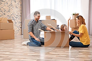 Happy family playing with cardboard box in their house. Moving day