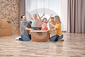 Happy family playing with cardboard box in their new house.