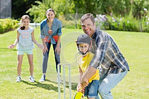 Happy family playing cricket together
