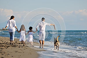 Happy family playing with dog on beach