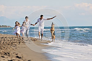 Happy family playing with dog on beach