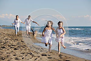 Happy family playing with dog on beach