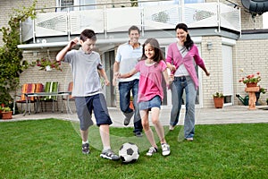 Happy family playing football in their backyard