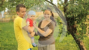 Happy family playing in the garden with the baby. Mom, dad, son, smile and laugh