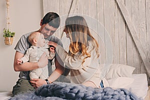 Happy family playing at home on the bed. Lifestyle capture of mother, father and baby