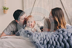 Happy family playing at home on the bed. Lifestyle capture of mother, father and baby