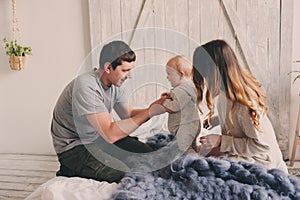 Happy family playing at home on the bed. Lifestyle capture of mother, father and baby