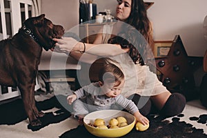 Happy family playing at home with dog. Mother and baby boy eating cookies