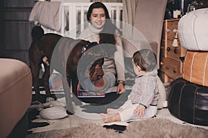 Happy family playing at home with dog. Mother and baby boy eating cookies