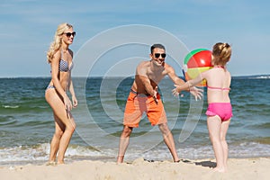 Happy family playing with inflatable ball on beach