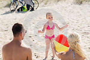 Happy family playing with inflatable ball on beach