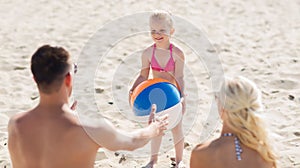 Happy family playing with inflatable ball on beach