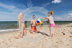 Happy family playing with inflatable ball on beach photo